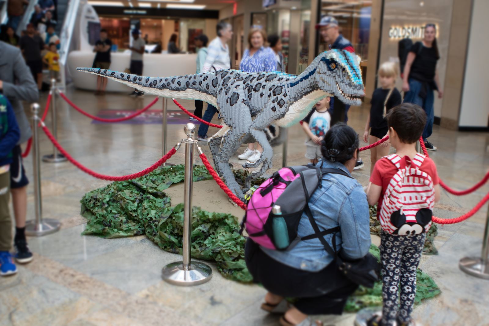 Woman and a child looking at a dinosaur made from toy bricks