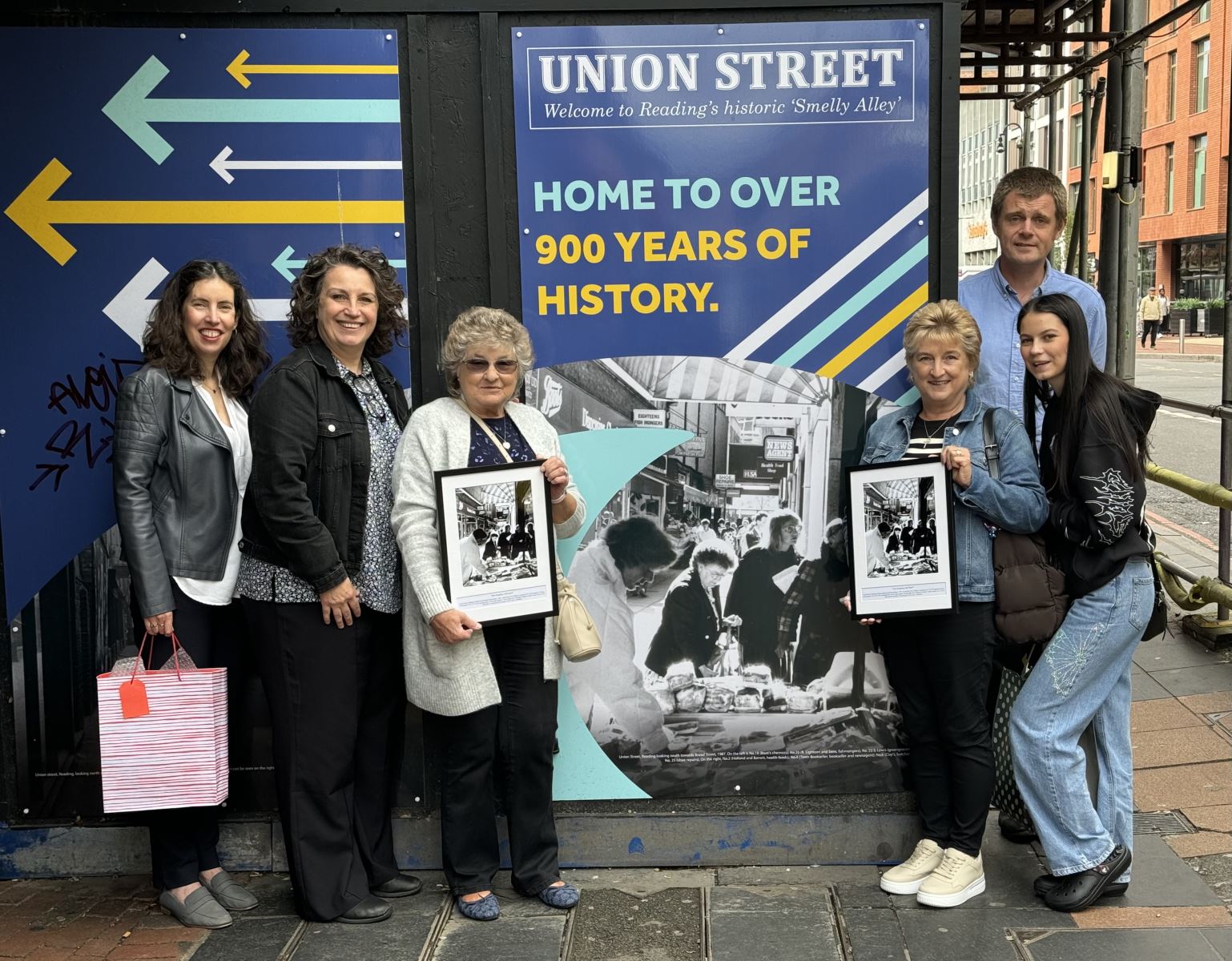 Group of people stood at the end of Union St, Reading, holding framed photos of the street from early 1900s